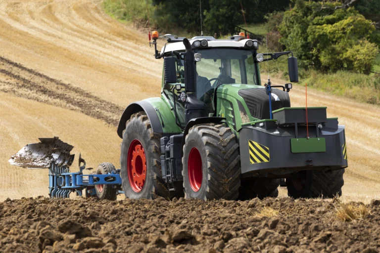 Tractor verde en el lodo, con neumaticos | Gomas de caucho, negras con aros rojos, utilizado en el sector de la agricultura